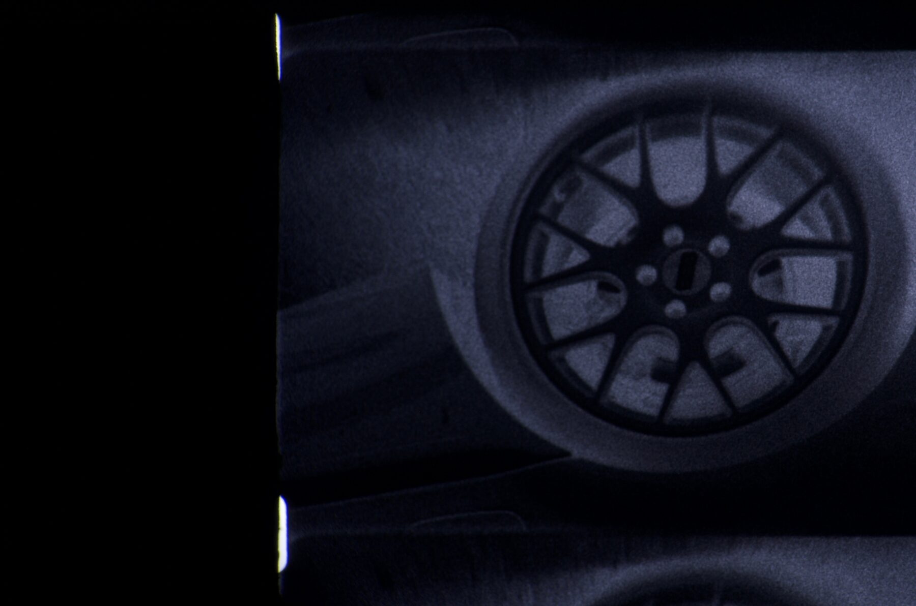 Blue-toned 16mm close-up of a car wheel