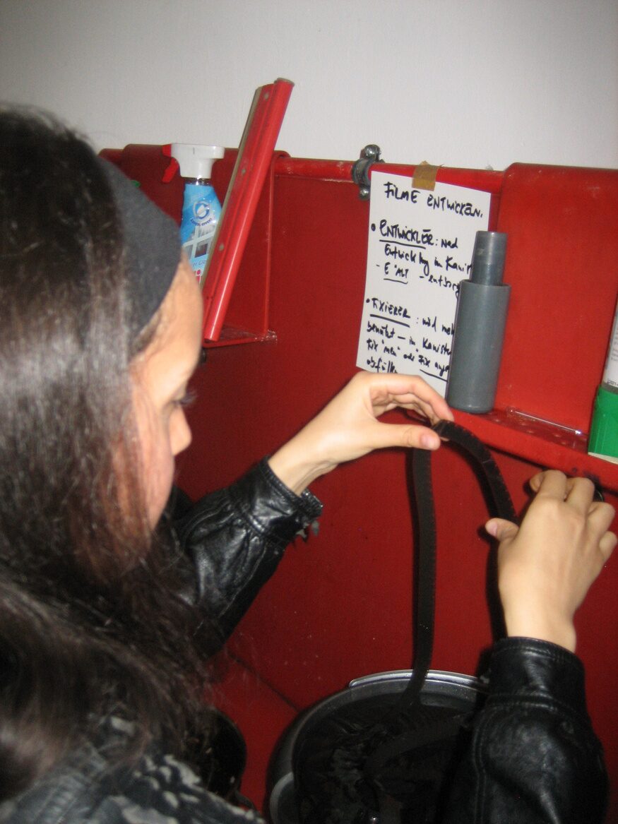 A strip of film being handled beside a red processing tank