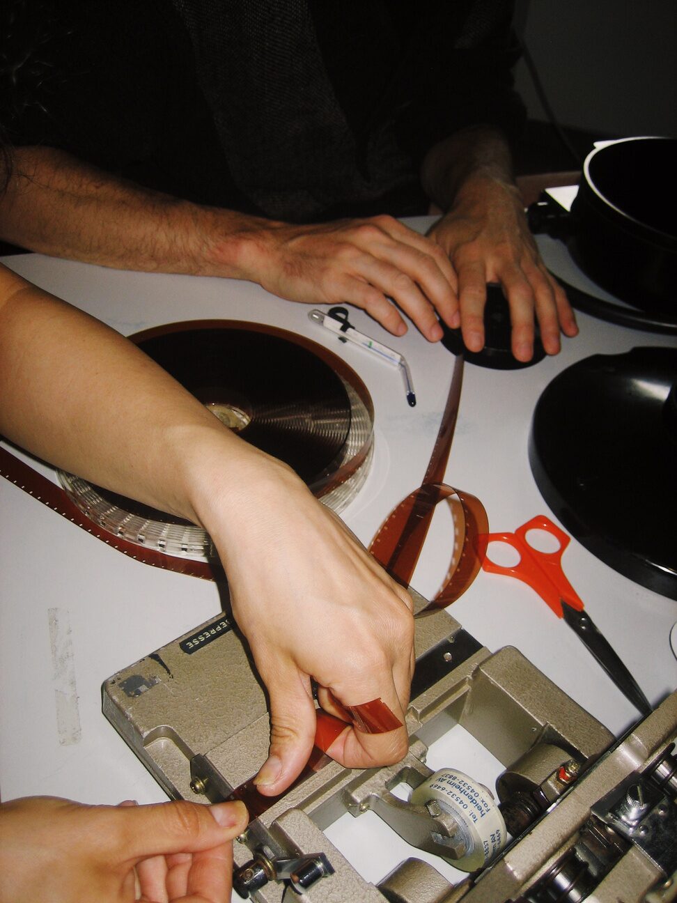 Hands cutting and handling film beside reels and scissors