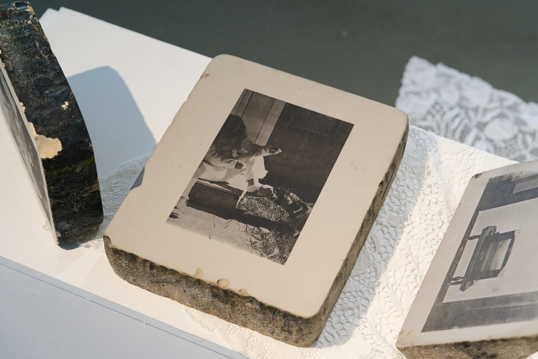 Several photographic lithographic stones on a lace-covered surface