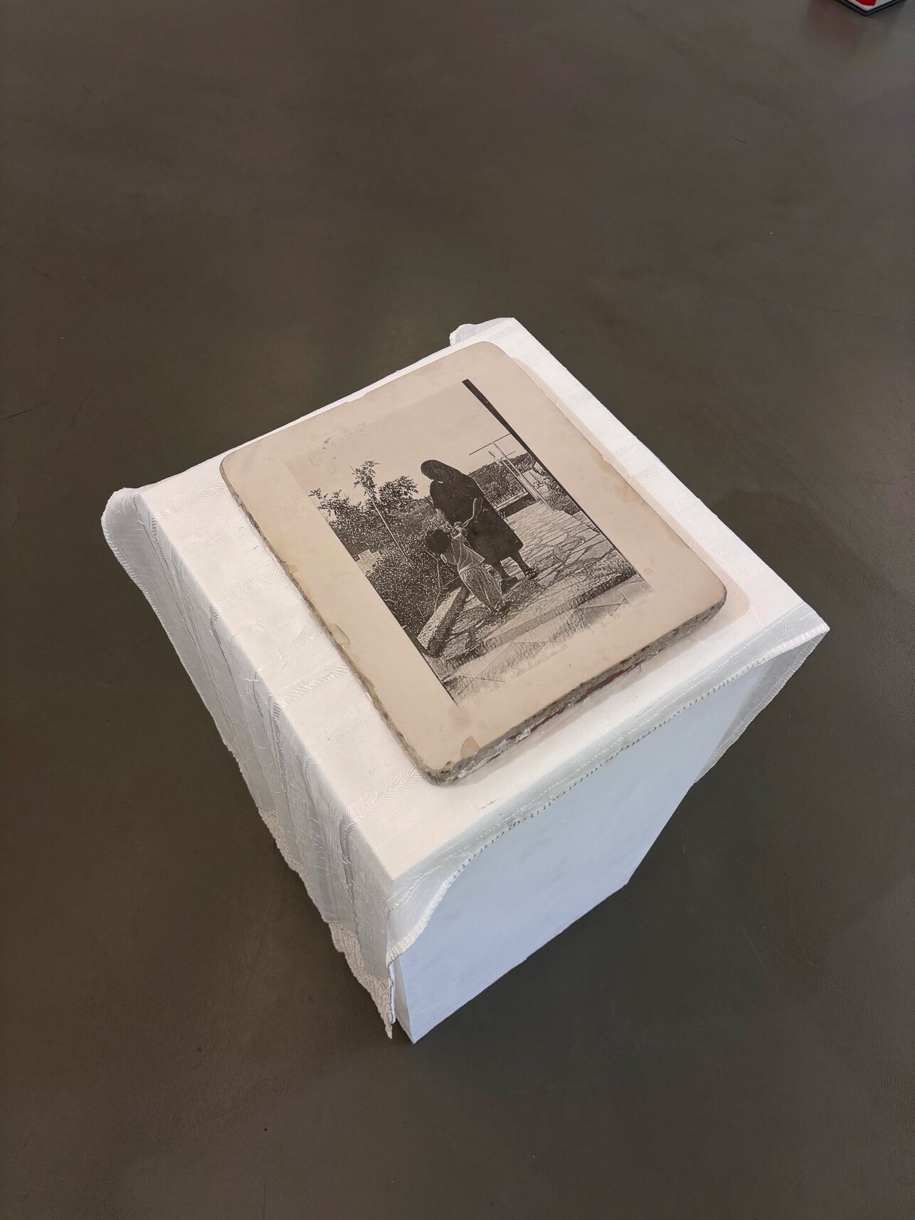 Lithographic stone with a family photograph displayed on a small covered plinth